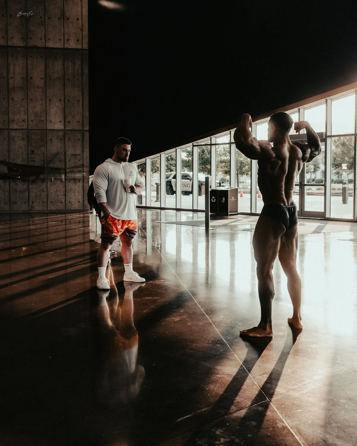 A Trademark coach assessing an athlete's bodybuilding pose